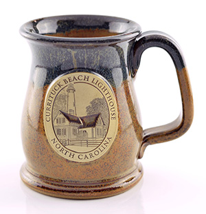 Warm tan speckled with dark navy blue glaze, and a beautiful lighthouse illustration plaque on coffee mug